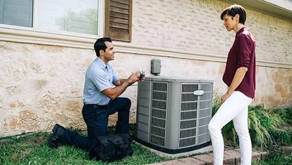 HVAC technician explaining outdoor AC service to a homeowner